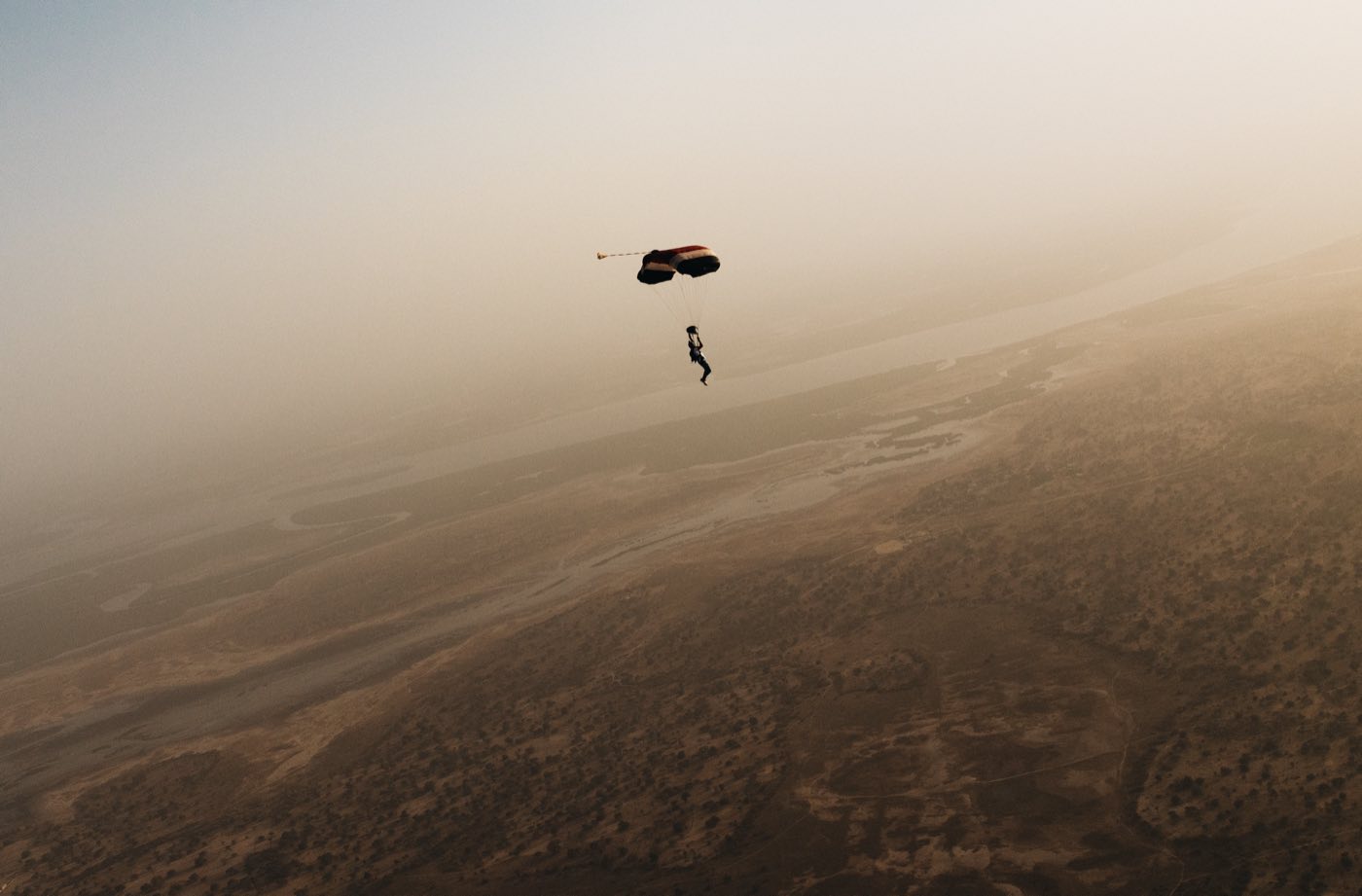 Un parachutiste sous voile dans une brume dorée