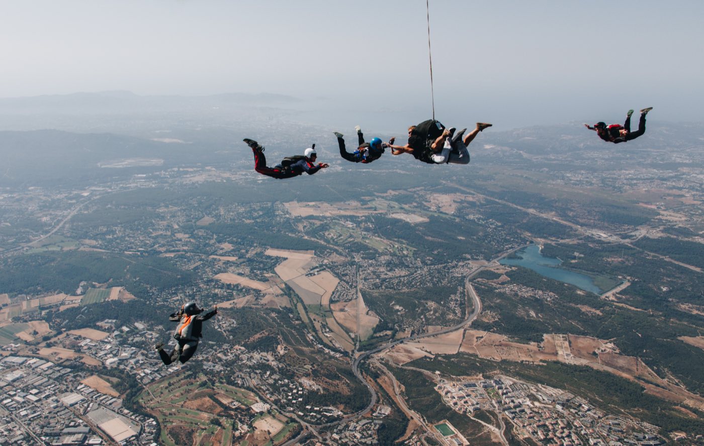 Plusieurs parachutistes en chute libre au-dessus d'une vallée