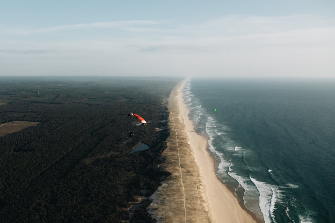 Vue aérienne d'une voile rouge au-dessus d'une plage et de l'océan