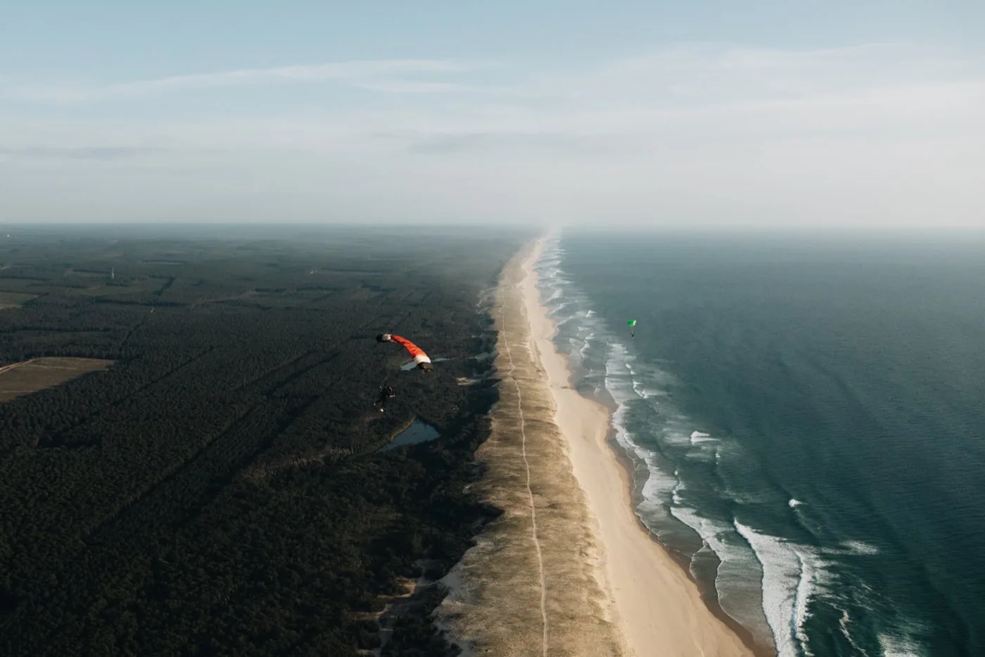 Vue aérienne d'une voile rouge au-dessus d'une plage et de l'océan