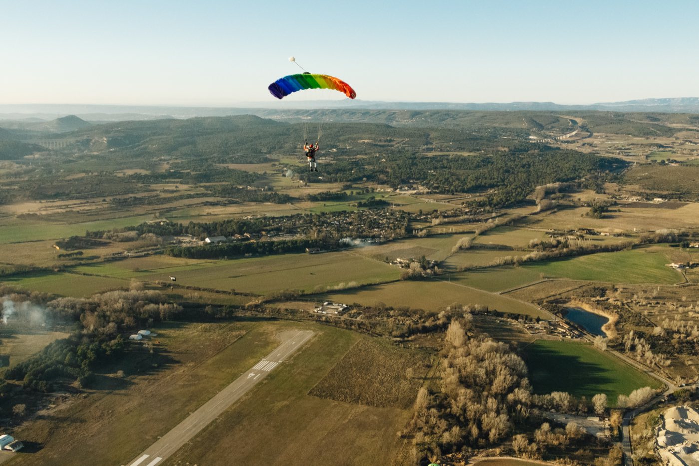 Voile aux couleurs de l'arc-en-ciel au-dessus de la campagne et d'une piste d'aérodrome